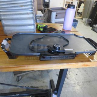 Presto electric griddle with temperature control on a wooden table; black, good condition, non-stick surface, plug attached.