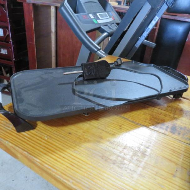 Presto electric griddle, black, missing grease cup, with power cord, on wooden surface.