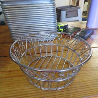 9x4 round stainless steel fast food basket with decorative swirls, used condition. Stack of similar baskets in background.