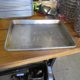 13x9.5 sheet pan in used condition, slight rust along edges, placed on a wooden table with other kitchen items nearby.