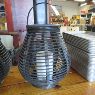 Black metal lantern with battery-operated candle inside. Features a wire frame design and a handle, ideal for decor.