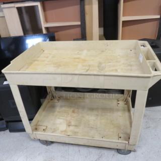 Tan utility cart on casters, 40x26x34 inches. Dual shelves with raised edges, handle, well-used with visible wear.