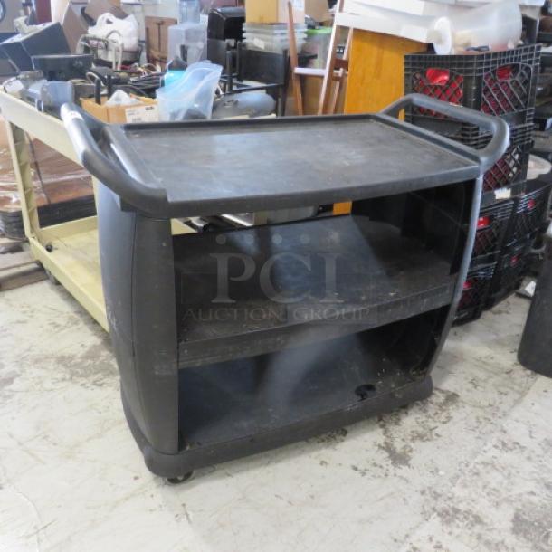 Black Carlisle 3 shelf cart on casters, size 42x20x40 inches. Durable design with curved handles, showing signs of use.