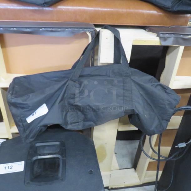 Black equipment bag with dual handles, rectangular shape, and visible white tag marked "67." Appears in good condition.
