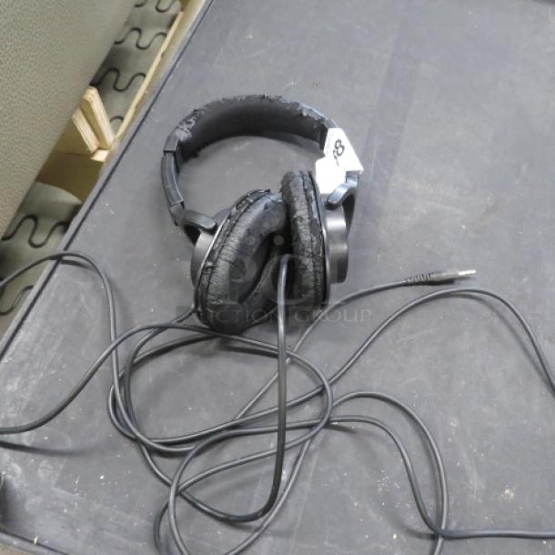 Roland RHS headphones, worn condition, black, coiled cord, visible wear on ear pads, over-ear design.