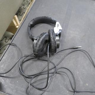 Roland RHS headphones, worn condition, black, coiled cord, visible wear on ear pads, over-ear design.