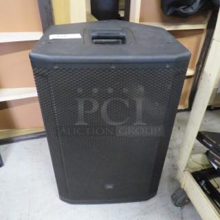 JBL SRX Series speaker, black, sturdy casing, integrated handle on top, slight wear, ideal for professional audio use.