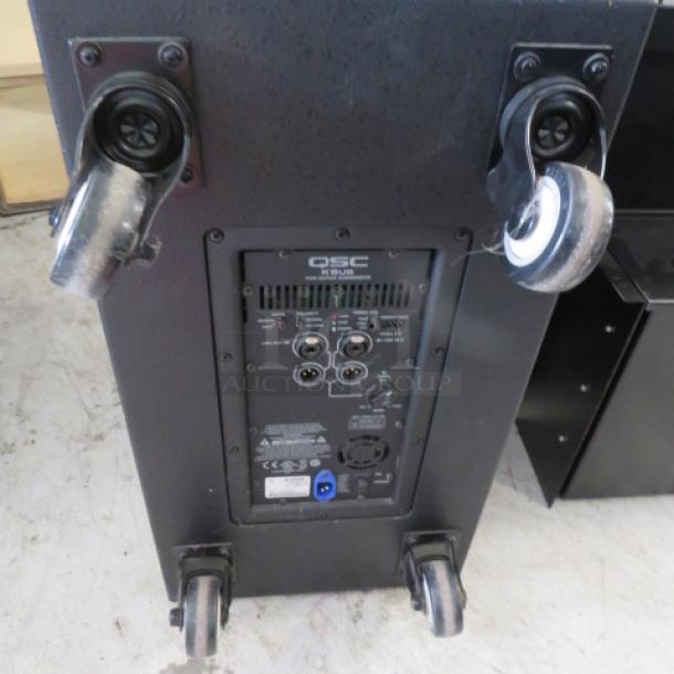 QSC K SUB subwoofer on casters, model panel visible. Features XLR inputs/outputs. Price: $1095.00.