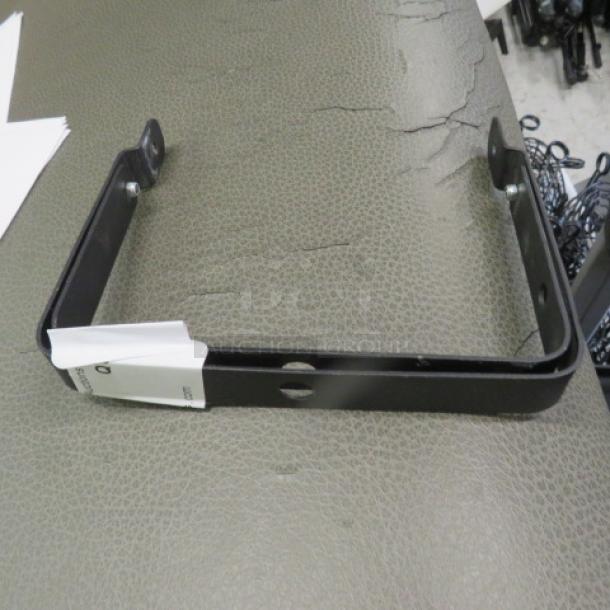 Black metal bracket with mounting holes, in good condition. Includes attached label. Suitable for structural support.