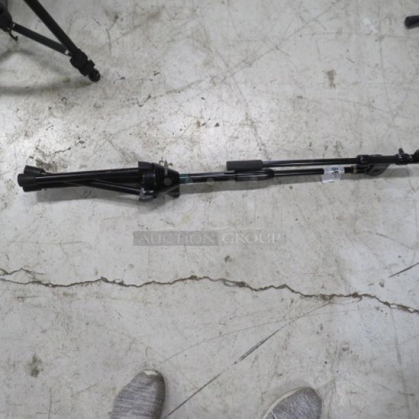 Dr Pro mic stand, black, adjustable, compactly folded, on concrete floor. Condition appears used but functional.