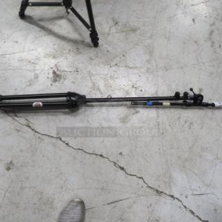 Collapsible mic stand with tripod base, black finish, shows signs of wear. No visible brand markings.