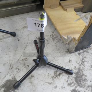 Adjustable black tripod stand with three sturdy legs, labeled "178," in good condition; ideal for musical instruments or equipment.