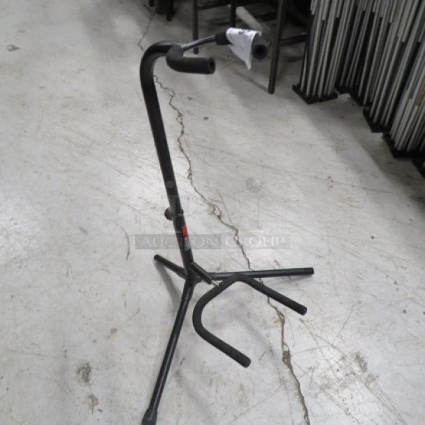 Adjustable black metal instrument stand in good condition, featuring a tripod base and rubber padding. Ideal for supporting various instruments.