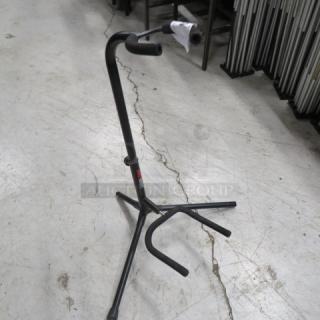 Adjustable black metal instrument stand in good condition, featuring a tripod base and rubber padding. Ideal for supporting various instruments.