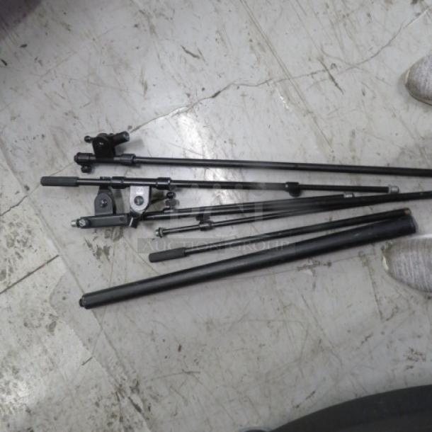 Lot of miscellaneous black metal rods and brackets on a concrete floor, varying lengths, condition appears used.