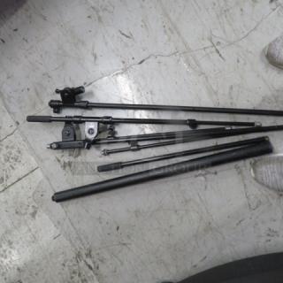 Lot of miscellaneous black metal rods and brackets on a concrete floor, varying lengths, condition appears used.