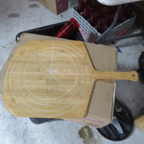 MPI wooden pizza paddle, 16x25 inches, with circular grid design. Used condition with visible markings.