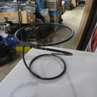 Black metal table top pizza pan holder, spiral design, sturdy condition, ideal for kitchen or dining use.