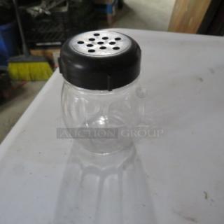 Clear glass cheese/pepper shaker with black perforated lid, model 12XBID, in good condition.