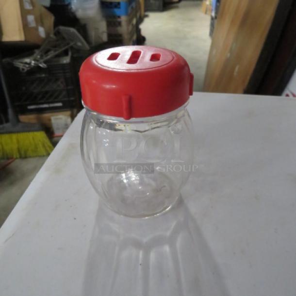 Clear glass cheese/pepper shaker with a red plastic lid, model 12XBID. In good condition, suitable for kitchen use.