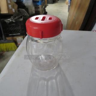 Glass cheese/pepper shaker with a red plastic lid, model 12XBID, used condition, visible minor wear.