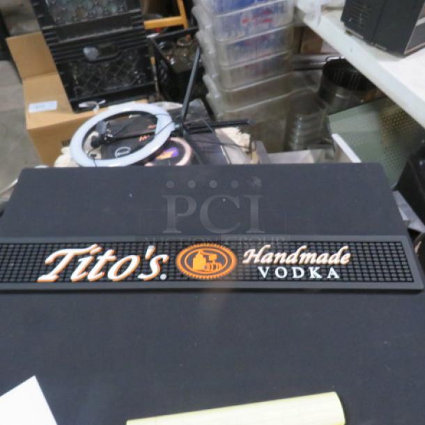 Tito's Vodka bar mat, black with orange and white logo, used condition, text reads "Tito's Handmade Vodka."