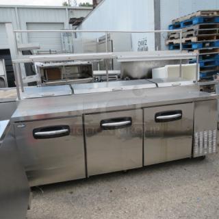 Turbo Air PT93 3-door prep table with 3 racks, overshelf, 2 ticket rails, on casters. 115V, 93x32x69. Condition: not cooling.