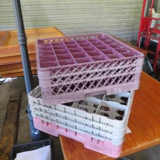 Assorted dishwasher racks, stacked, various colors, used condition, grid design, for industrial kitchen use.
