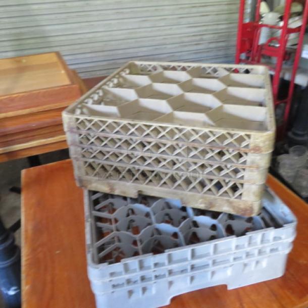 Assorted dishwasher racks stacked; various sizes and styles. Used condition with visible signs of wear. Ideal for commercial use.
