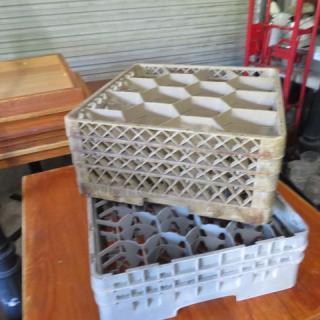 Assorted dishwasher racks stacked; various sizes and styles. Used condition with visible signs of wear. Ideal for commercial use.
