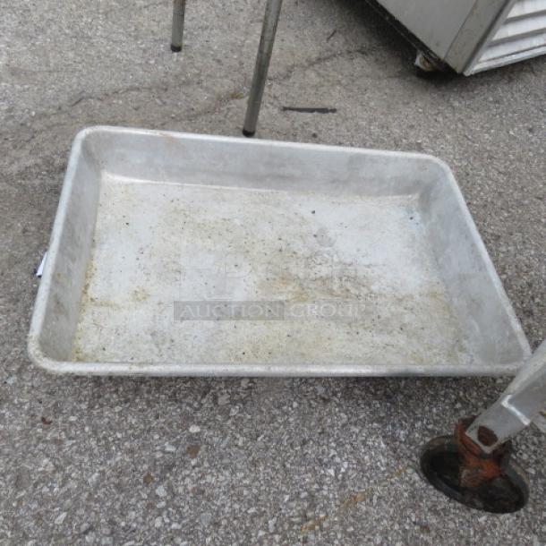 Large metal roasting pan, 26x18 inches, showing signs of wear and discoloration. Ideal for high-capacity cooking.