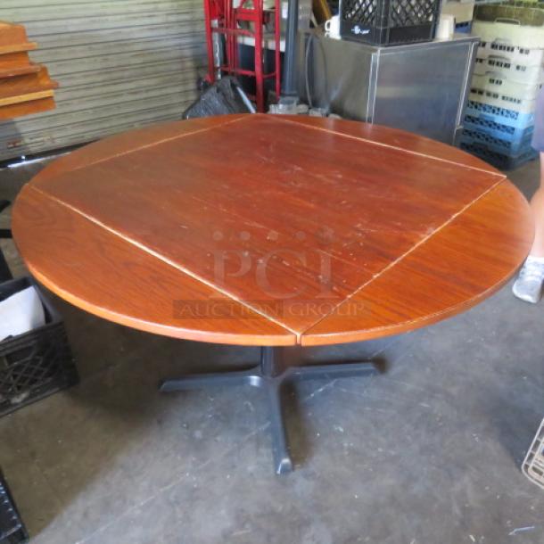 Solid wood table with flip-up sides on a pedestal base, expands to 42-inch round, dimensions 36x36x29, minor wear visible.