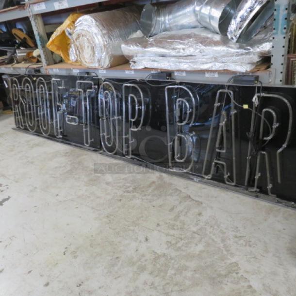 Two-piece "ROOFTOP BAR" neon sign, 148x30.5 inches. Clear tubing on black backing, in good condition, ideal for bar decor.