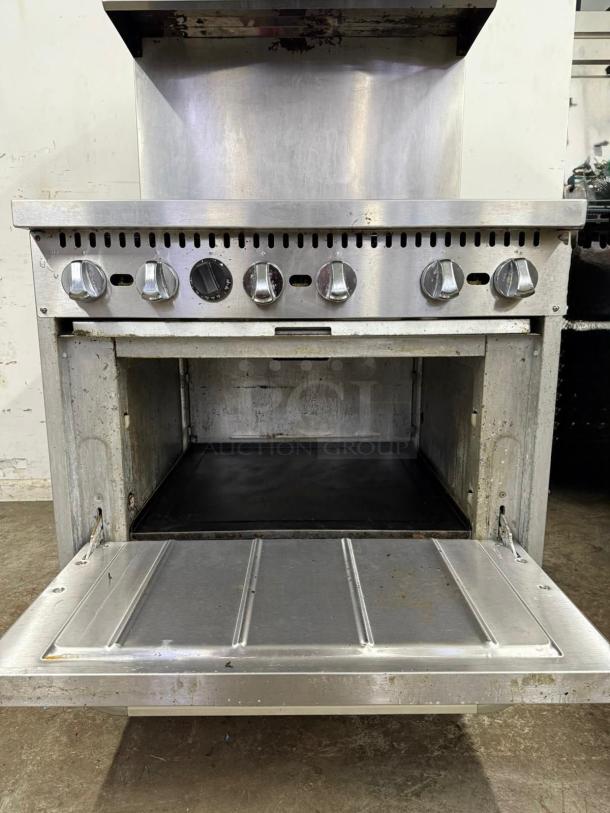 Stainless steel 6 burner gas stovetop and oven, open door view, clean condition, with visible knobs and control panel.