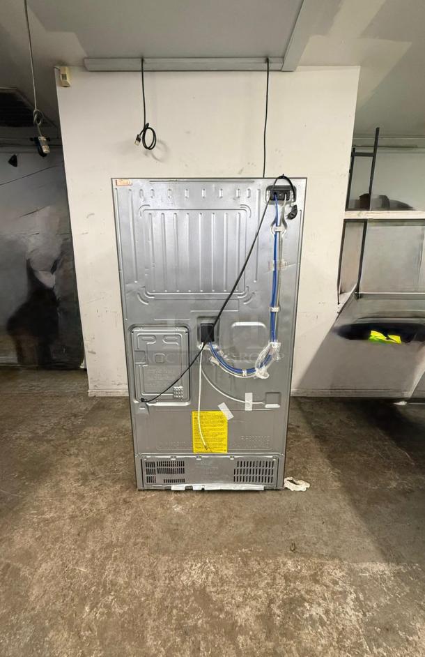 Back view of a Samsung 4-Door French Door Smart Refrigerator. Visible wiring and labels. Stainless steel exterior.