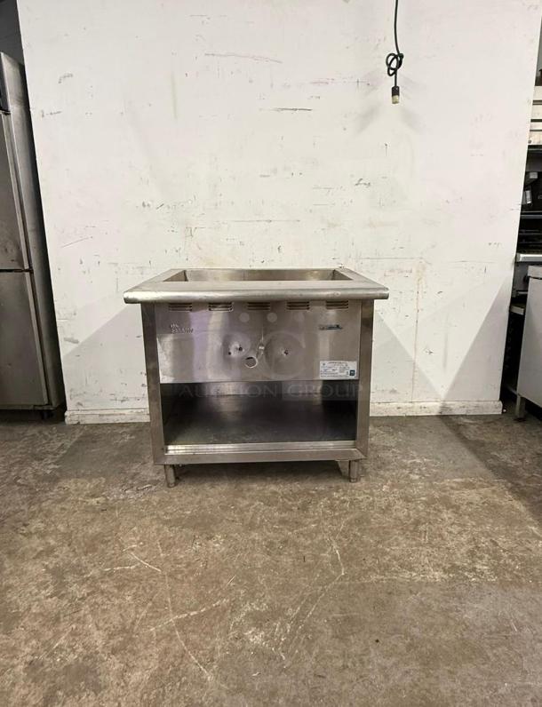Stainless steel undercounter steam table, features open storage, durable, with visible control knobs and manufacturer's label.
