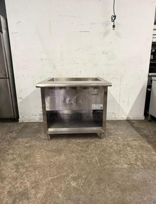 Stainless steel undercounter steam table, features open storage, durable, with visible control knobs and manufacturer's label.
