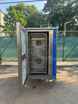Cleveland combi oven, stainless steel, open door showing interior with racks, good condition, blue control panel on side.