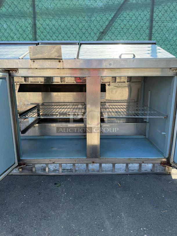 Delfield 4472M-30M-A1 stainless steel 3-door mega top refrigerated sandwich prep table, 72in, showing open interior shelves.