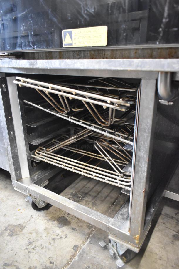 Baxter BV400G stainless steel rotating rack oven with pan rack, natural gas, self-cleaning, commercial casters, caution label visible.