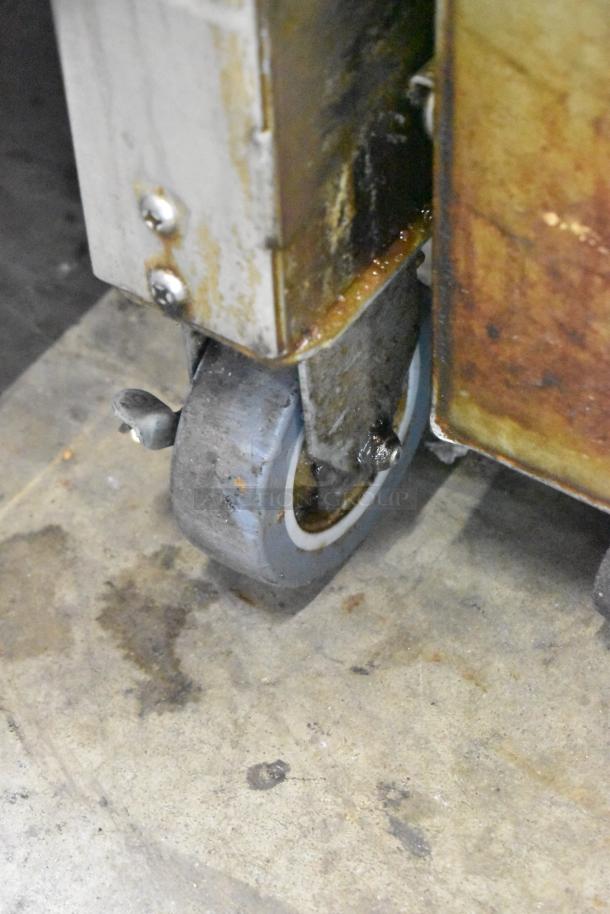 Giles GEF-530-VH deep fryer wheel showing rust and grease, indicating wear. Stainless steel frame visible.