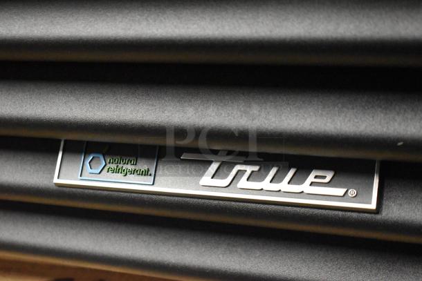 True GDM-23-HC cooler close-up showing "natural refrigerant" and True logo on black metal surface.