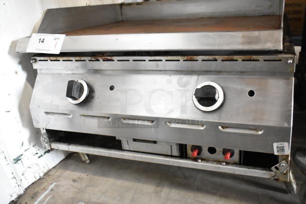 Stainless steel commercial countertop gas griddle with dual control knobs, used condition, item tag visible.