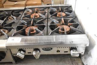 Royal stainless steel commercial 4-burner gas range, well-used condition, prominent control knobs, and Royal branding.