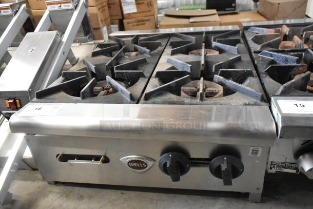 Wells stainless steel 4-burner countertop gas range, commercial use, worn condition, visible logo and control knobs.