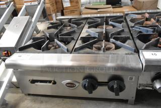 Wells stainless steel 4-burner countertop gas range, commercial use, worn condition, visible logo and control knobs.