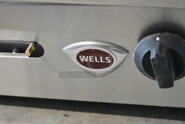 Wells stainless steel 4-burner gas range, commercial countertop model, featuring control knobs and Wells logo.