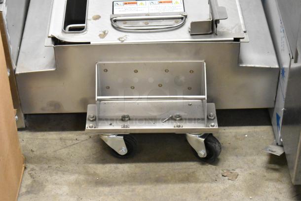 Metal commercial grease trap on casters in good condition, featuring sturdy stainless steel construction and visible warning labels.