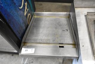 Stainless steel flat top griddle plate showing signs of use, with a slotted grease drain; auction tag number 23 visible.