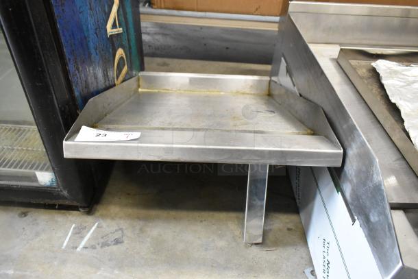 Stainless steel flat top griddle plate in used condition, features a raised edge and sturdy base, with a visible tag labeled "23".
